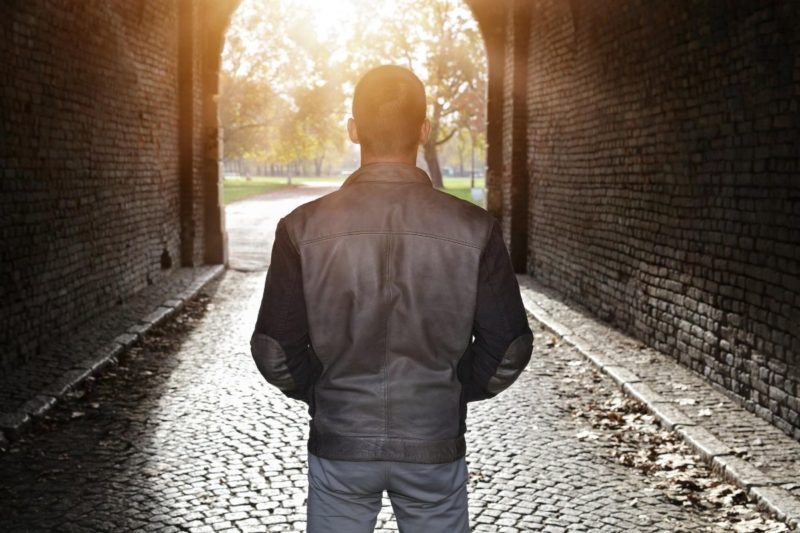 A man struggling with drug addiction looks out as the sun sets.