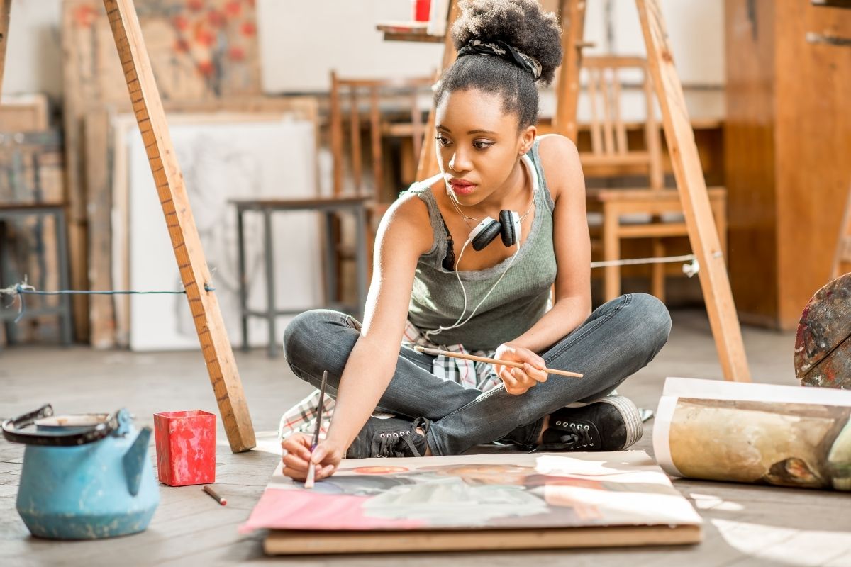 A woman paints on a canvas as a part of art therapy.