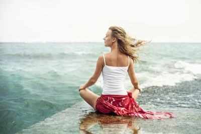 woman mediating on the beach