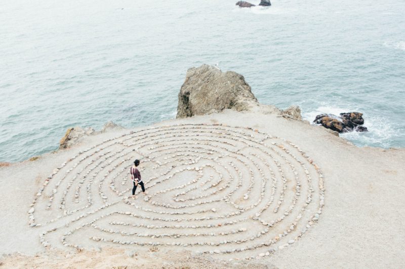 person on beach observing a sand maze