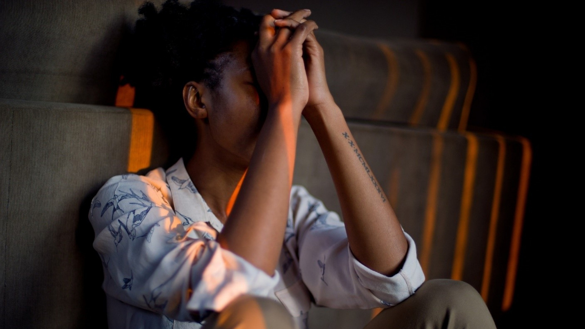 woman leaning on couch with hands on forehead