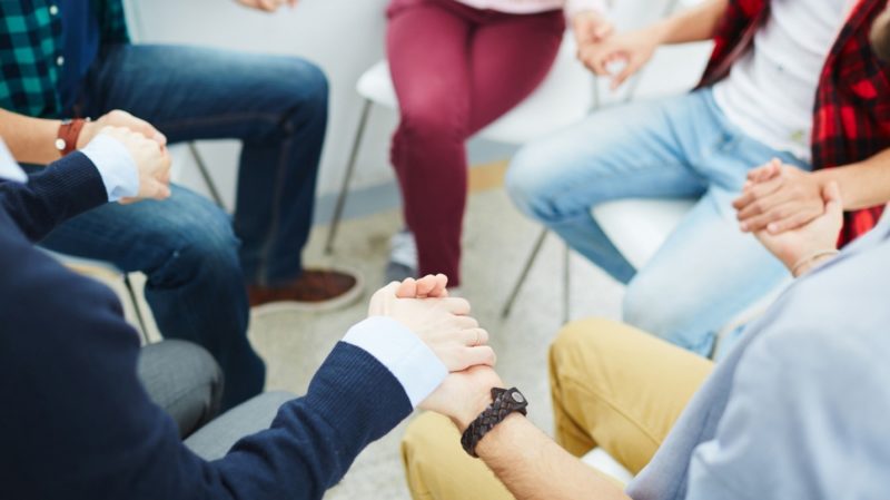 group of people sitting holding hands