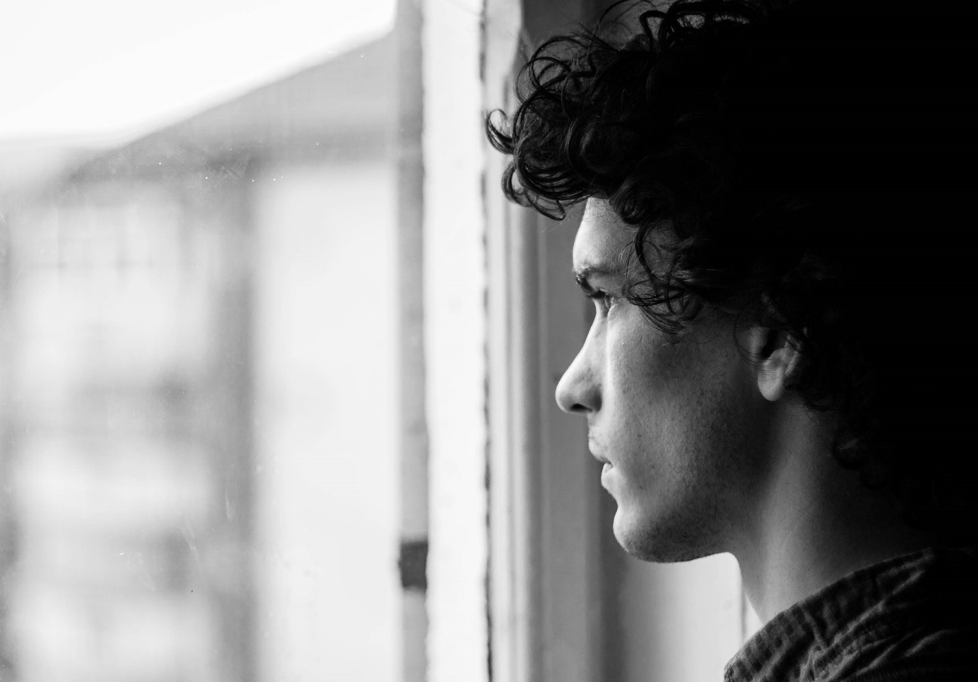 man looking out window black and white