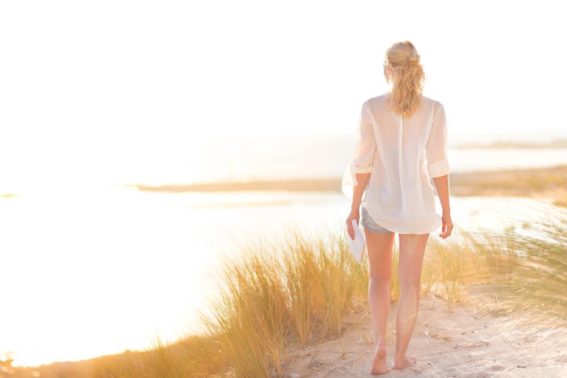 woman walks along beach at drug addiction treatment center in florida