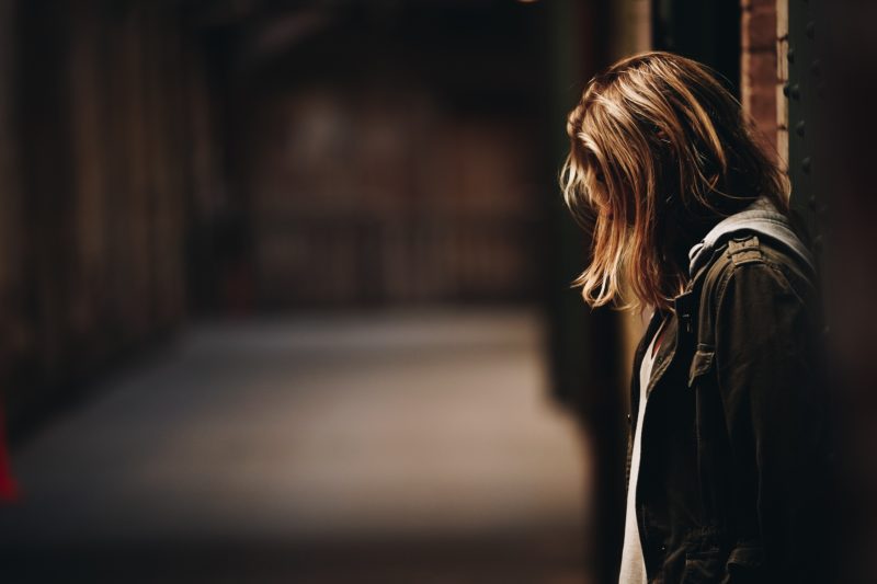 young woman leaning on wall with head down